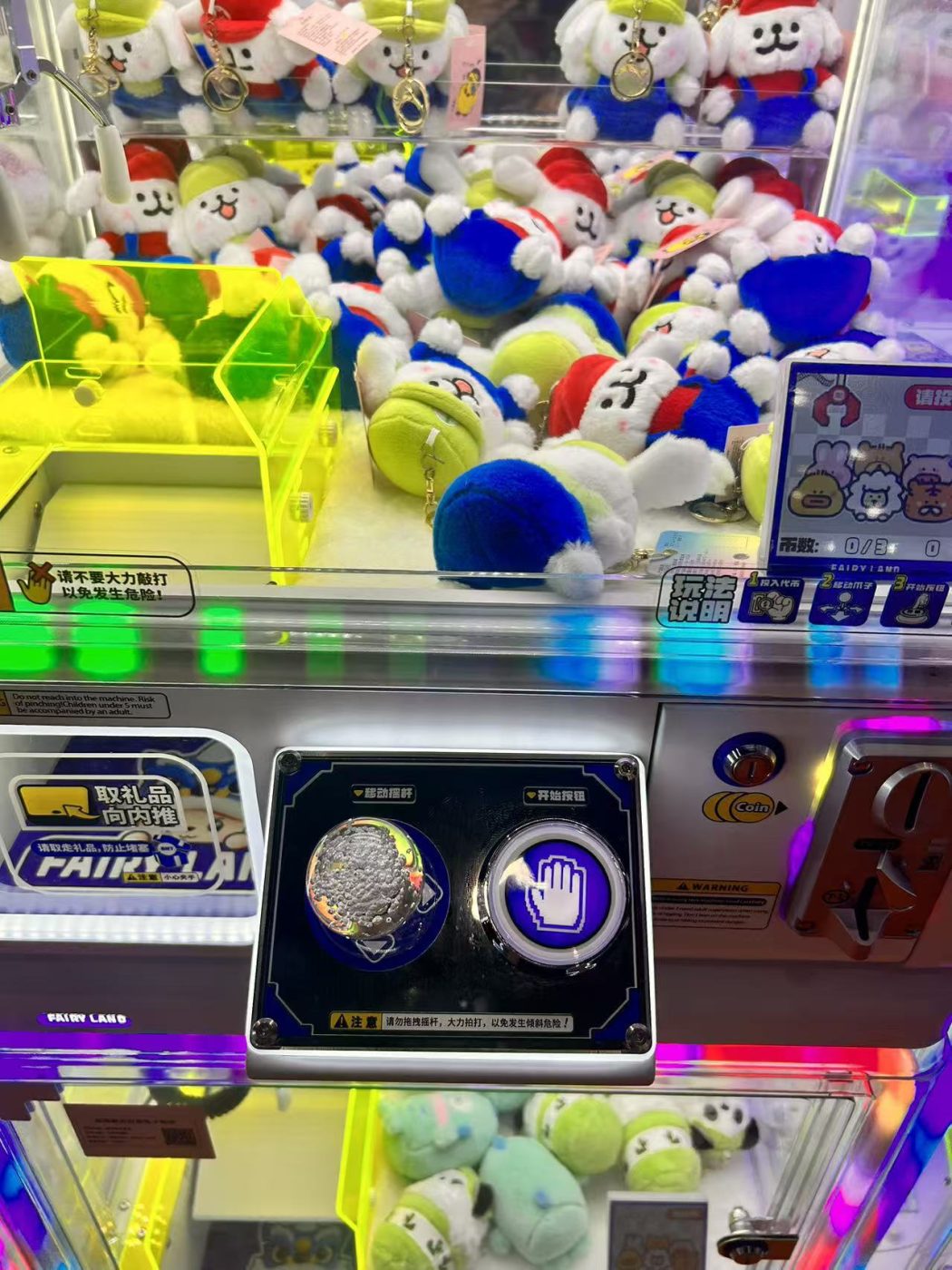 Claw machine control plate with an iridescent joystick ball and an illuminated start button