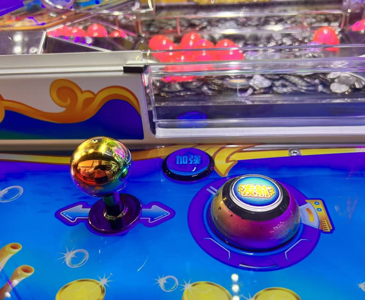 Iridescent joystick ball top and iridescent dome fire button on a coin pusher control panel