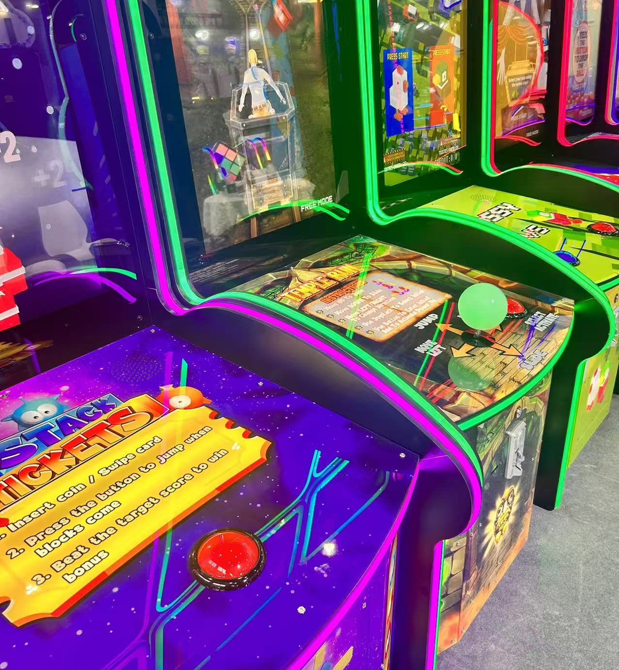 Row of ticket redemption cabinets with large red dome buttons and ball-top joysticks